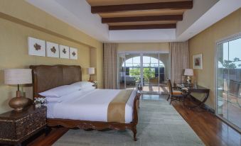 a large , well - made bed with white linens and a wooden headboard is in the center of a room with two lamps , a at Anantara Desert Islands Resort & Spa
