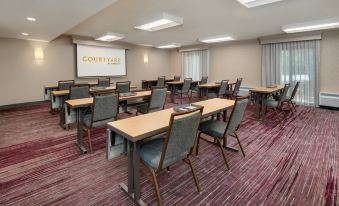 a conference room with multiple tables and chairs , a projector screen , and curtains on the windows at Courtyard Birmingham Homewood