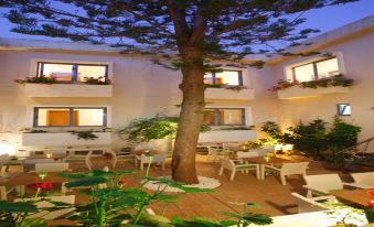 a hotel courtyard with a large tree in the center , surrounded by tables and chairs at Sofia Hotel