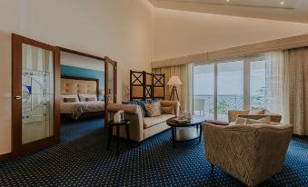 a luxurious hotel room with a king - sized bed , a couch , a chair , and a dining table at Renaissance Wind Creek Aruba Resort