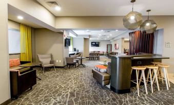 a modern hotel lobby with various seating options , including couches , chairs , and a dining table at SpringHill Suites Florence