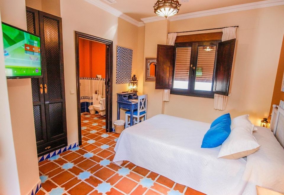 a bedroom with a bed , blue and white pillows , a tv , and a sink in the corner at La Esperanza