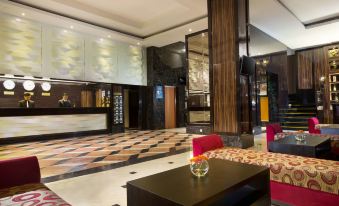 a modern hotel lobby with a large reception desk , red chairs , and a checkered floor at Best Western Plus Makassar Beach