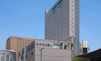 a large building with a blue sign is surrounded by other buildings in a city at Hotel Kanazawa