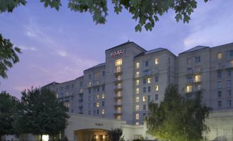 "a large hotel with a pink logo and the word "" hyatt "" on top , surrounded by trees and buildings" at Hyatt Regency Long Island