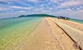 a beautiful beach with clear blue water , white sand , and people enjoying the sunny day at Hoang Trung Hotel