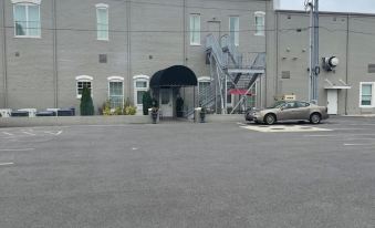 a parking lot with a car and a helicopter in front of a building , under an overcast sky at Meadows Hotel