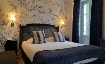 a large bed with a black headboard and white linens is situated in a room with a window at Hotel Restaurant Notre Dame