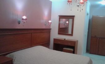 a cozy bedroom with a bed , a dresser , and a mirror , decorated with pink lighting and chandeliers at Paradise