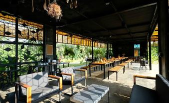 a restaurant with several dining tables and chairs , some of which are occupied by people at Baan Rai Darun Home Stay and Scenery Raft