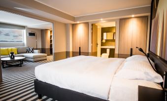 a large bed with white sheets and a black headboard is in a room with striped flooring at Simon Hotel