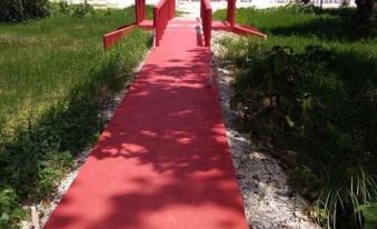 a red wooden bridge spanning across a body of water , with trees in the background at Holiday Inn Beach Resort