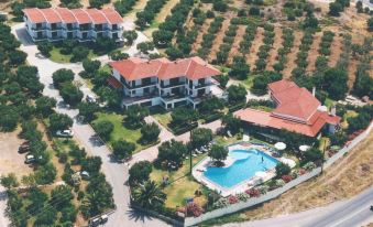 aerial view of a large villa complex surrounded by trees , with a swimming pool in the foreground at Asteris Village