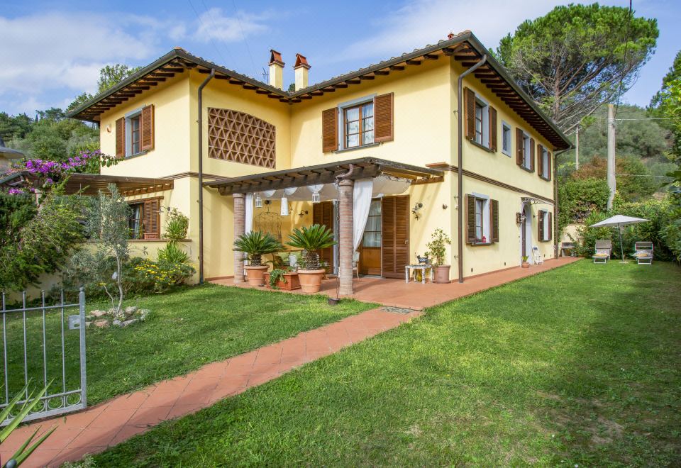 a yellow two - story house with a red brick walkway leading up to the front door at La Rondine