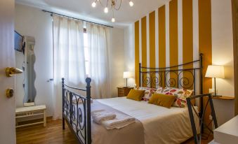 a large bed with white and gold bedding is in a room with wooden floors , a window , and a chandelier at La Rondine