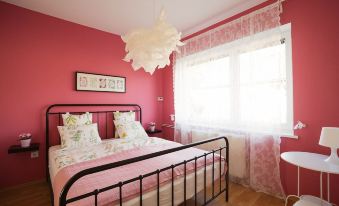 a cozy bedroom with a pink and white color scheme , featuring a large bed and a window at Garden Apartment
