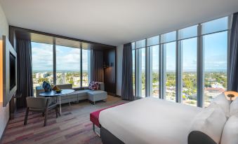 a modern hotel room with large windows offering a view of the city , a comfortable bed , and a desk at Aloft Perth