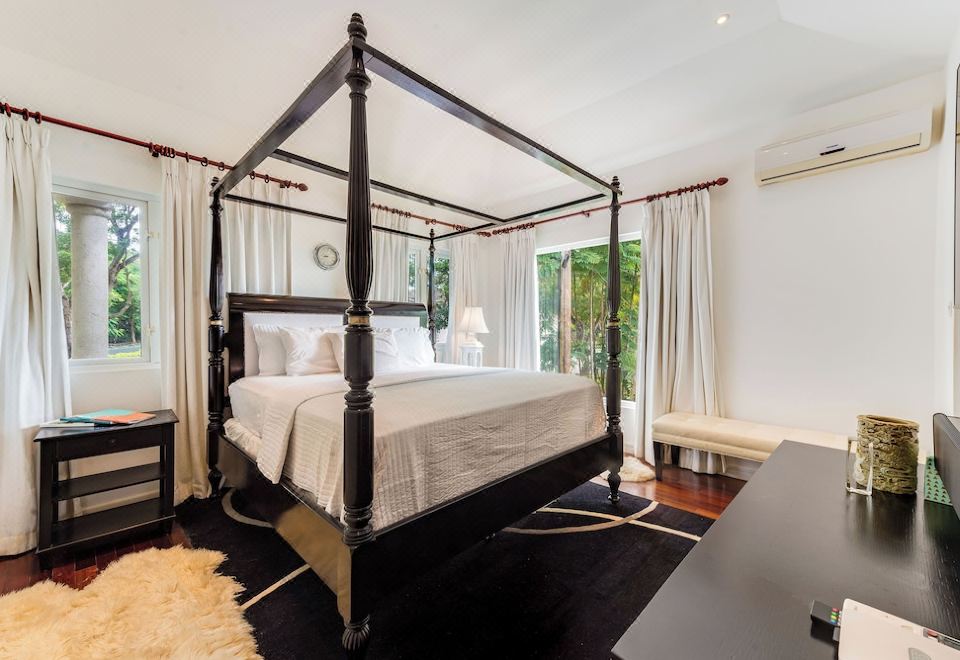a large bed with a black metal frame is in the middle of a room with white walls at The Palms Resort
