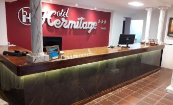 "a reception desk with a red wall behind it and the words "" hotel hermitage "" written on it" at Hotel Hermitage