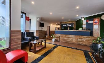 a modern hotel lobby with a reception desk , chairs , and potted plants , along with a couch and coffee table at Hotel Bliss