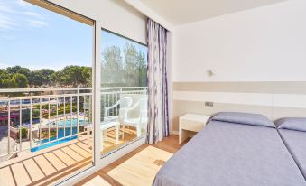a bedroom with a bed and sliding glass doors leading to an outdoor pool area at Mll Palma Bay Club Resort