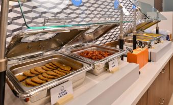 a buffet - style dining area with a variety of food items , including multiple trays filled with various dishes at Holiday Inn Express & Suites Williams