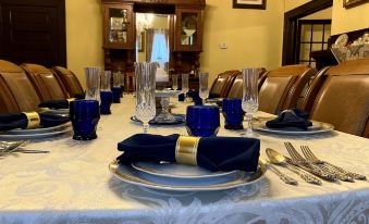 a dining room with a long table set for a meal , complete with blue napkins and wine glasses at Whole Hearts Bed and Breakfast