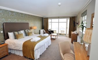 a large bed with white linens and a gold blanket is in the middle of a room with a window at Beech Hill Hotel & Spa
