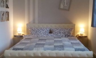 a bedroom with a white bed , two lamps on either side of the bed , and a blue and white quilt on the bed at Villa Regina
