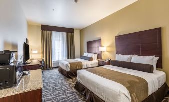 a hotel room with two beds , a tv , and a desk , all neatly arranged in a hotel - style bedroom at Cobblestone Hotel & Suites - Chippewa Falls