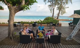 a group of people sitting on a wooden deck near the beach , enjoying each other 's company at Divi Southwinds Beach Resort