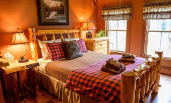 a cozy bedroom with a wooden bed , plaid bedding , and two nightstands on either side of the bed at RoosterComb Inn
