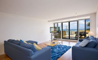 a modern living room with blue couches , wooden floors , and large windows offering views of the ocean at Grand Pacific Hotel