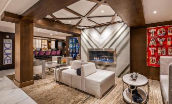 a modern lounge area with a white couch , coffee table , and an electric fireplace in the background at The Kingsley Bloomfield Hills - a DoubleTree by Hilton