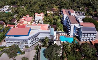 a bird 's eye view of a resort with multiple buildings , a pool , and palm trees at Le Meridien Goa, Calangute