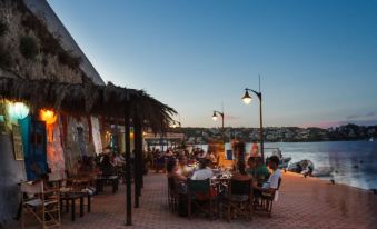 a group of people are gathered around tables in an outdoor setting with the ocean in the background at Hotel Victori