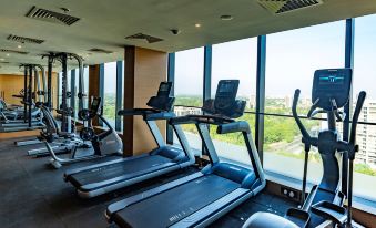 a gym with treadmills and stationary bikes lined up in front of a large window at DoubleTree by Hilton Ahmedabad