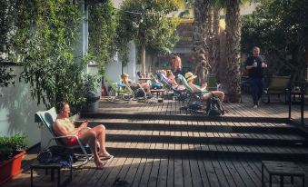 a group of people relaxing on lounge chairs on a wooden deck , enjoying each other 's company at Hamra Urban Gardens