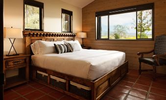 a large bed with white linens is situated in a bedroom with wooden walls and windows at La Lomita Ranch