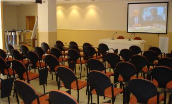 a conference room with rows of chairs arranged in a semicircle , and a projector on the wall at Hotel Vent de Mar