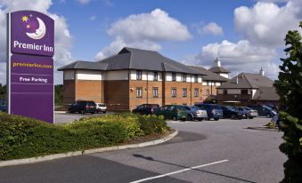 a large brick building with a purple sign , surrounded by a parking lot and trees at Premier Inn Gillingham Business Park