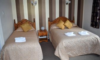 a hotel room with two beds , one on the left and one on the right side of the room at Rettendon Lodge