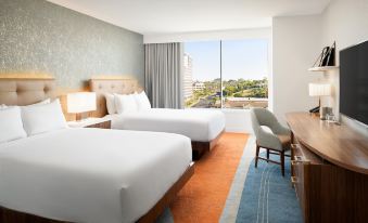 a hotel room with two beds , a window overlooking a cityscape , and a chair near the window at Hilton Los Angeles-Culver City, CA