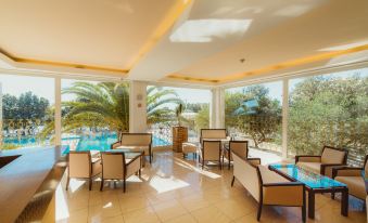 a modern , well - lit room with large windows offering views of a swimming pool and palm trees at La Luna Hotel - All Inclusive