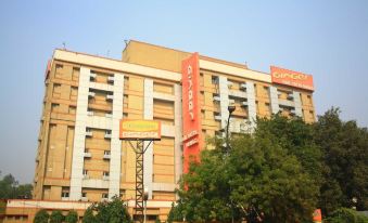 A large building with an orange sign on the side is visible against a blue sky at Ginger Hotel  Delhi Rail Yatri Niwas  Irctc