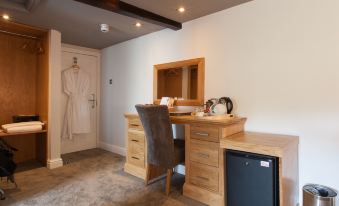 a hotel room with a desk , chair , and wardrobe , as well as a small bathroom with a sink at The Inn at Brough