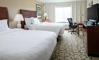 a hotel room with two beds , a desk , and a chair , all neatly arranged in the room at Hilton Garden Inn Omaha West