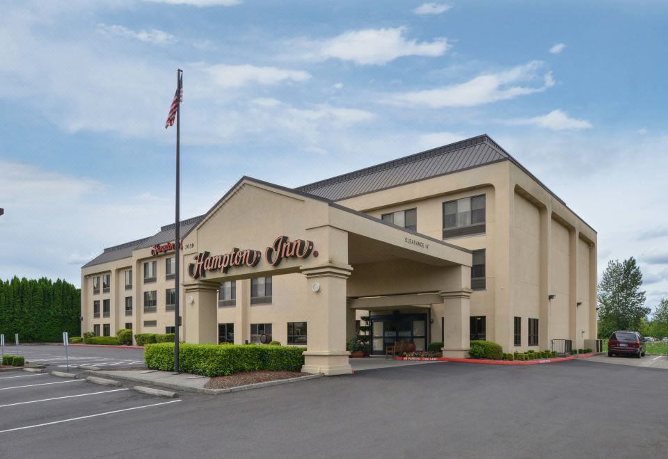the hampton inn hotel with its name displayed in brown letters , along with a flagpole and clear blue sky at Hampton Inn Portland East