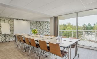 a large conference room with multiple rows of chairs arranged in a semicircle around a long table at Center Parcs les Bois Francs