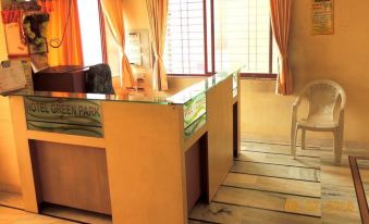 a hotel lobby with a reception desk , two chairs , and a tv mounted on the wall at Hotel Greenpark